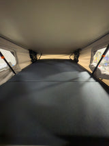 RV rental pop-up tent interior: a spacious sleeping area with a dark grey mattress.