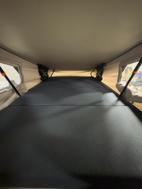 RV rental pop-up tent interior: a spacious sleeping area with a dark grey mattress.