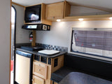 RV rental kitchen: microwave, sink, fridge, fire extinguisher, and cozy dinette for travel.