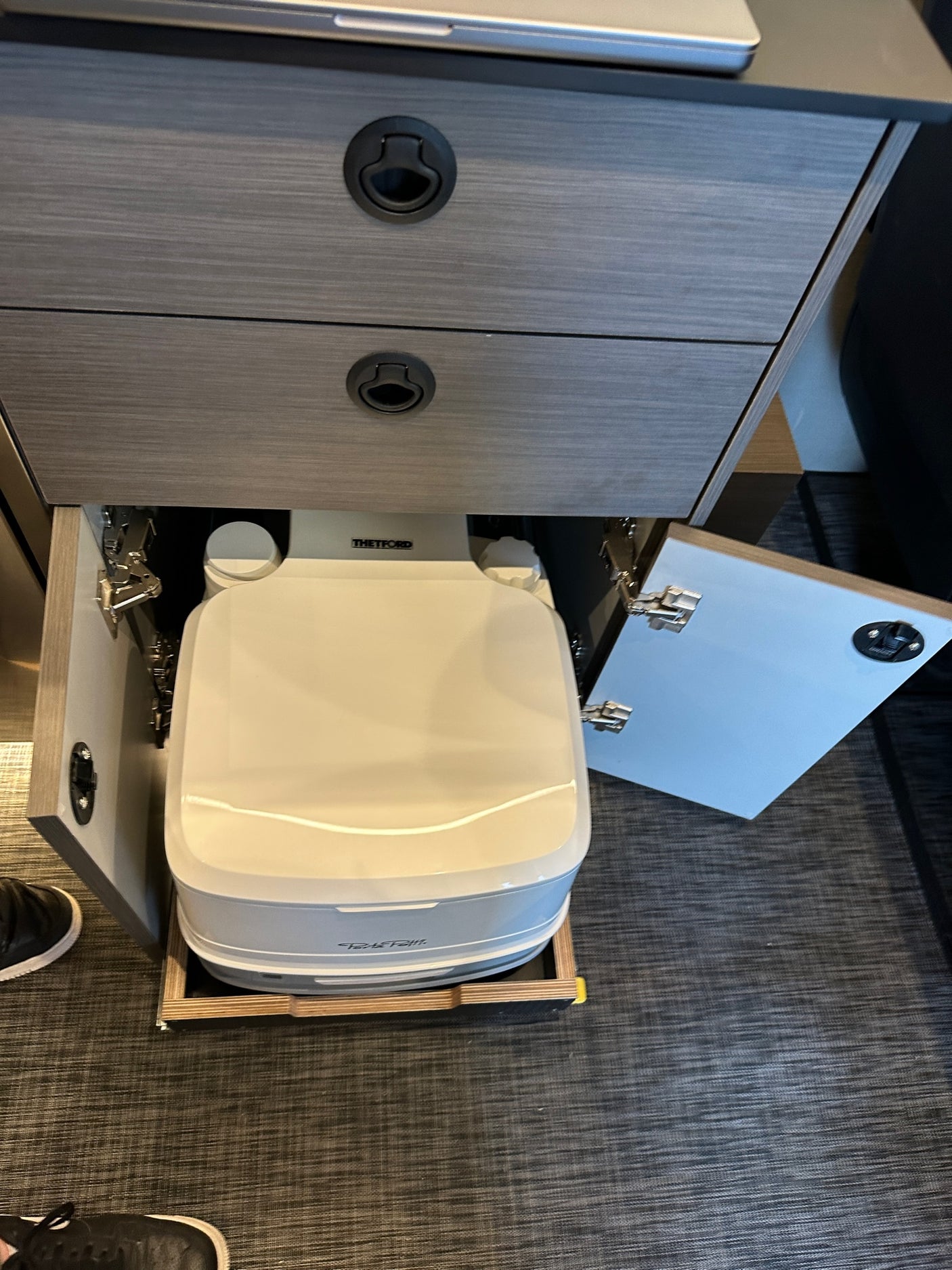 Discover the ingenious pull-out Thetford portable toilet in this RV rental, neatly hidden within custom cabinetry.