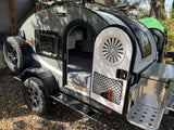 This compact Boondock teardrop trailer, ideal for rv rental, shows its cozy bed, AC, and outdoor adventure gear.