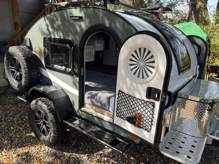 This compact Boondock teardrop trailer, ideal for rv rental, shows its cozy bed, AC, and outdoor adventure gear.