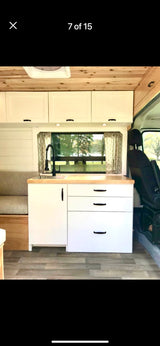 RV rental interior: cozy camper van kitchen with sink, cabinets, and panoramic window view. Perfect for mobile living.