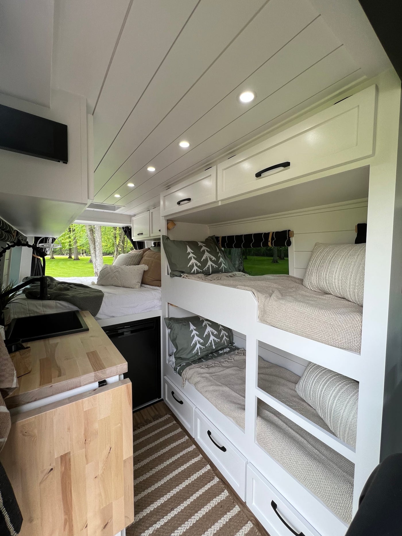 RV rental interior: cozy bunk beds, main sleeping area with outdoor view, and compact kitchen. — photo 2