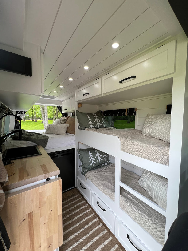 RV rental interior: cozy bunk beds, main sleeping area with outdoor view, and compact kitchen. — photo 2