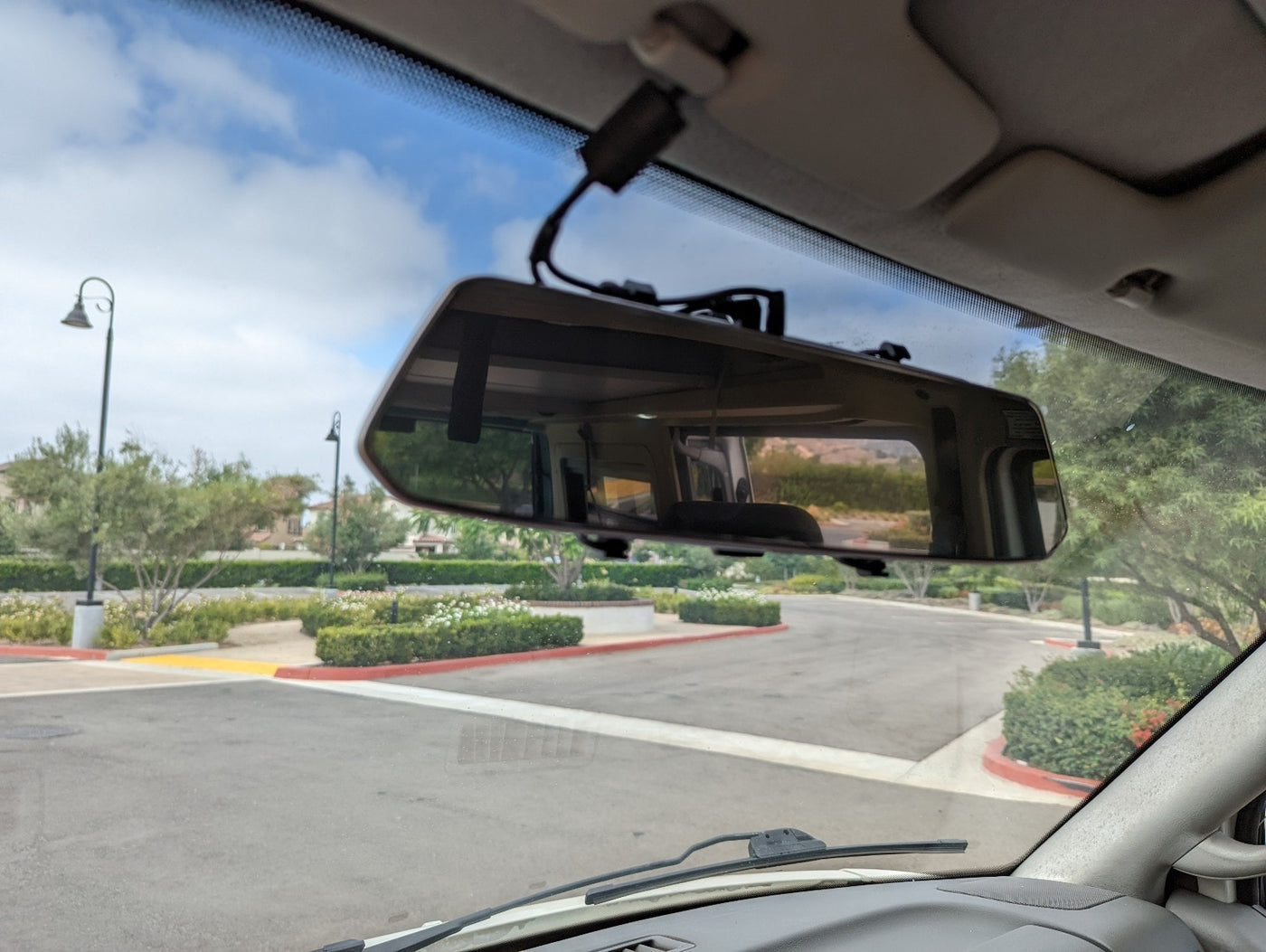 RV rental cockpit view: windshield shows road, trees; rearview mirror reflects the vehicle's interior. — photo 13