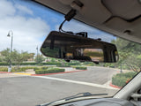 RV rental cockpit view: windshield shows road, trees; rearview mirror reflects the vehicle's interior.