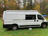 White Ram ProMaster camper van, ideal for rv rental adventures, parked on grass amidst autumn trees.