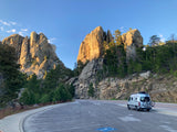 An RV rental parked at Mount Rushmore National Memorial, with the carved presidential faces and rugged landscape visible.