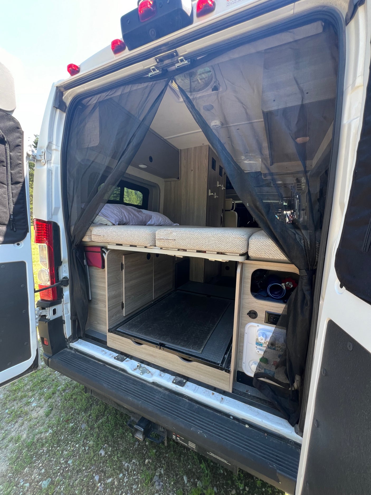 Rear view inside an **rv rental**, showcasing a comfortable bed, under-bed storage, and a practical mesh screen for ventilation.