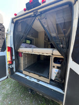 Rear view inside an **rv rental**, showcasing a comfortable bed, under-bed storage, and a practical mesh screen for ventilation.