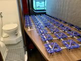 RV rental interior: compact bathroom with toilet and a bed base featuring purple mattress suspension modules.