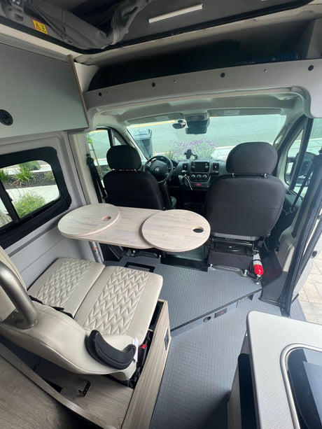Inside an RV rental: versatile camper van interior with swivel front seats, extendable table, and comfy bench seating.