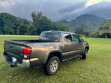 Grey Toyota Tacoma pickup truck on a vibrant green lawn with cloudy mountains. A robust choice for exploration, like an RV rental alternative.