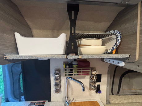 Organized RV rental kitchen area with shelves, sink, spice rack, and storage caddy, maximizing space for travelers.