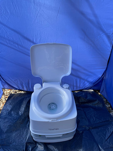 Portable Porta Potti toilet inside a blue privacy tent on a tarp, ideal for rv rental or camping sanitation.