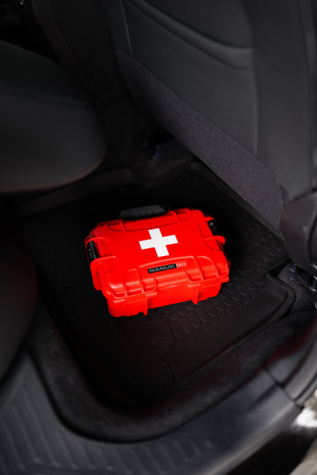 Essential red NANUK 903 first aid kit with white cross, ready on a rubber mat in an RV rental.