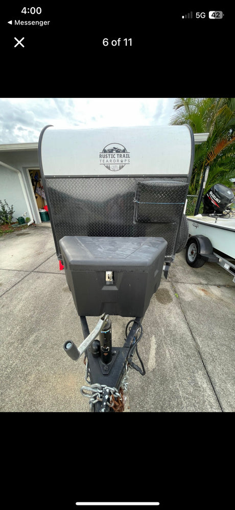 Front view of a Rustic Trail teardrop trailer, a compact RV rental option. Note the storage box & hitch. Ready for your camping trip!
