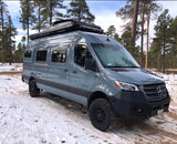 Adventure-ready grey Sprinter camper van for rv rental, parked in a snowy forest. Ideal for off-road exploration.
