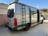 Modern gray Mercedes Sprinter RV rental van with a roof rack, ladder, and Starlink dish. The side door is open.