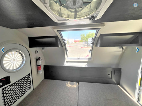Experience an RV rental! Interior with comfortable bed, open rear window, ceiling fan, and storage. Ready for adventure.