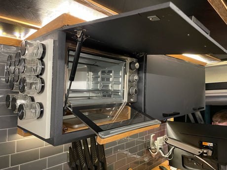 Compact rv rental kitchen: overhead cabinet with toaster oven, magnetic spice rack, and knife storage.