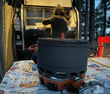 RV rental adventure: Person cooking dinner in the integrated camp kitchen with a portable stove setup.