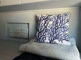 Cozy RV rental interior with blue coral pillow, soft waffle blanket, & "Catch a Wave" sign.
