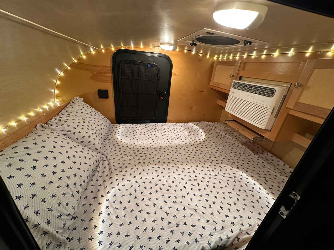  and bright lighting.|Cozy RV rental interior: a comfy bed with patterned pillows and quilts — photo 8