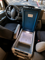 Inside an RV rental: a portable car cooler, lit up and ready for vanlife. Features a steering wheel with a cow print cover.
