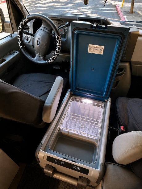 Inside an RV rental: a portable car cooler, lit up and ready for vanlife. Features a steering wheel with a cow print cover.
