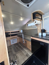 RV rental interior features a compact dinette, kitchenette with sink & fridge, plus AC. Ideal for cozy adventures.