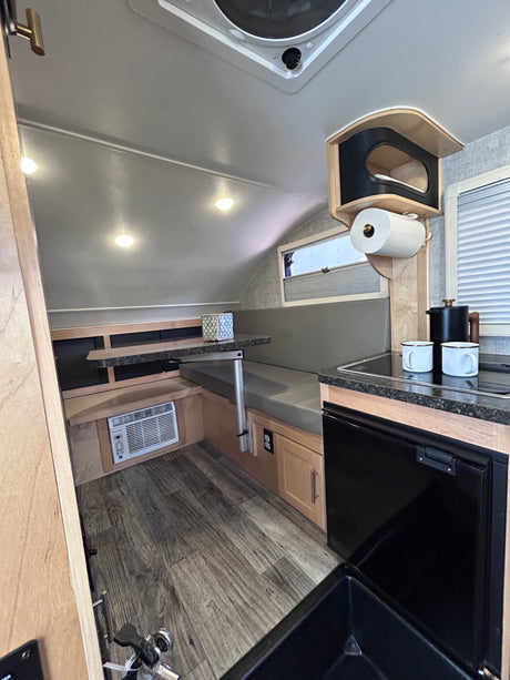 RV rental interior features a compact dinette, kitchenette with sink & fridge, plus AC. Ideal for cozy adventures.