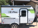 A compact, modern Flagstaff E-Pro travel trailer in white/gray with green trim, parked outside. Perfect for an rv rental adventure!