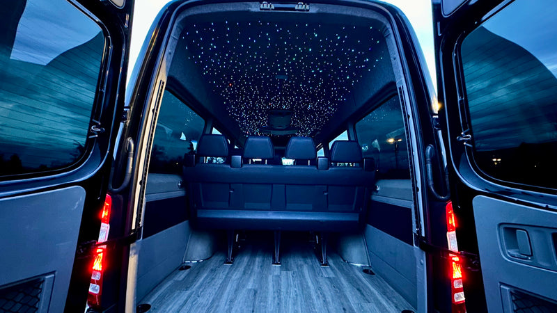 Luxury RV rental van: custom interior with dazzling starlight ceiling, rear seating, and wood-look floor, viewed from the open back. — photo 6