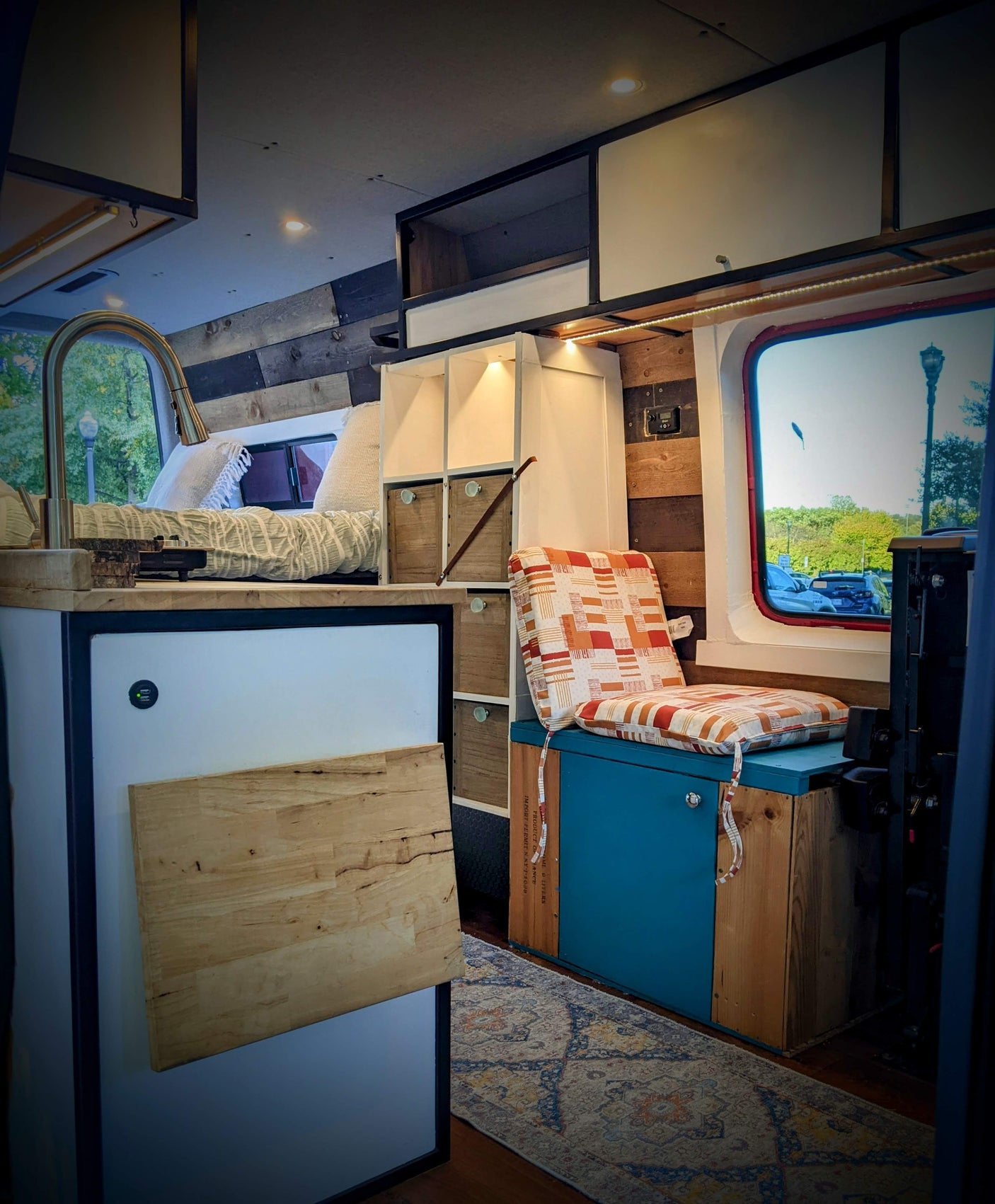 Inside this RV rental: a compact living space with a bed, sink, smart storage, and cozy seating.