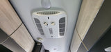 Overhead view inside an RV rental: AC unit, controls, vents, cabinets, and smoke detector on the ceiling.