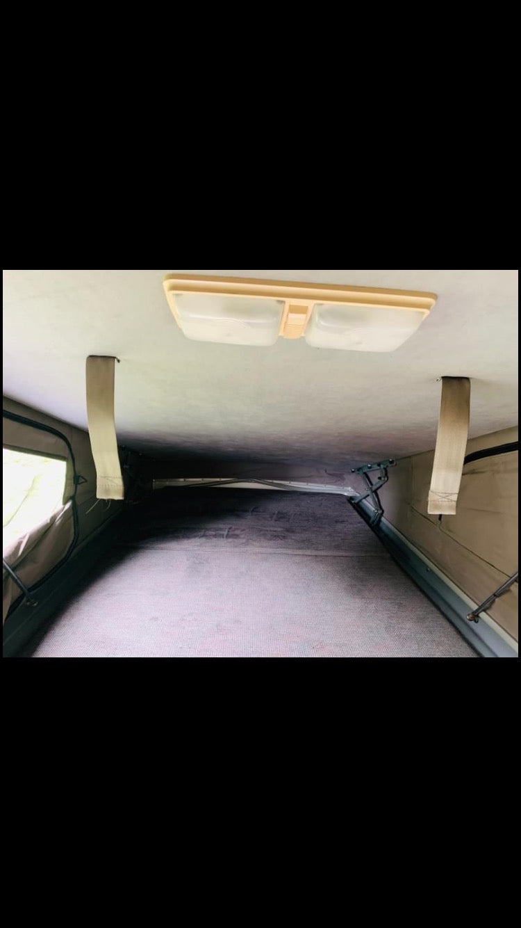 Inside an **rv rental** pop-top sleeping area, showing the textured floor, overhead light, and fabric walls. — photo 12