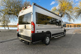 This silver Integra Coach Ethos camper van, ideal for an RV rental, is parked scenically by a lake at sunset.
