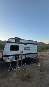 A Coleman RV rental parked at campsite #3 in a desert setting with mountain views, fully hooked up for adventure.