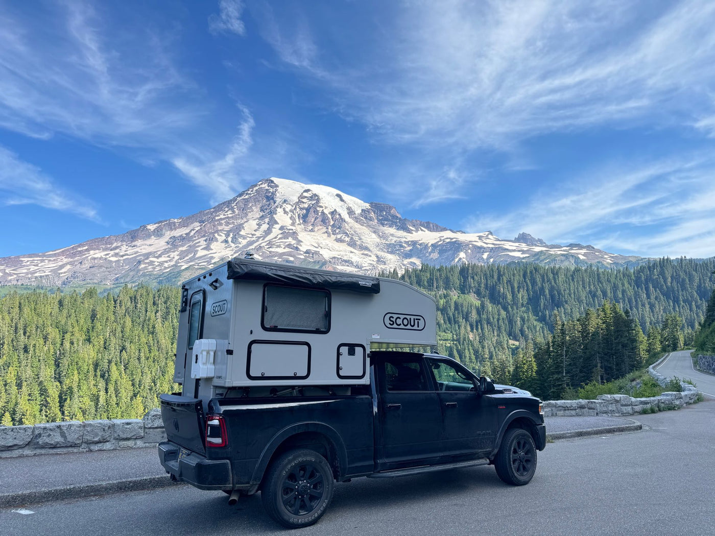 Explore with this RV rental: A black pickup truck with a Scout truck camper, parked at a scenic Mt. Rainier viewpoint amidst forests. — photo 9