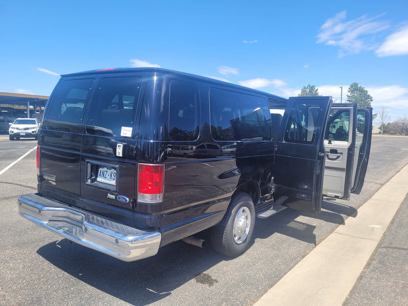  showing a large upholstered bench seat and cargo area.|Rear of a black Ford van — photo 7