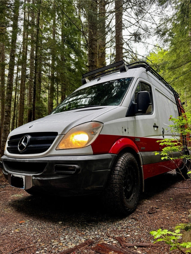 Mercedes Sprinter camper van, built for off-road adventure, perfect for rv rental, parked on a forest trail.