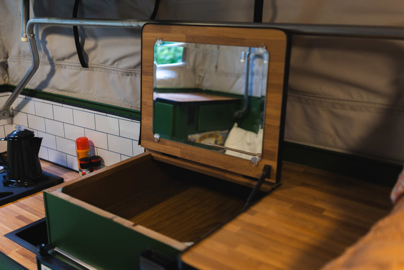 Inside an RV rental: a smart pop-up camper kitchen featuring wood countertops, sink, subway tiles, and a multi-use mirror/storage unit. — photo 10