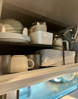 Neat kitchenware organization in an RV rental. Stacked plates, mugs, tumblers, and felt storage optimize compact space.