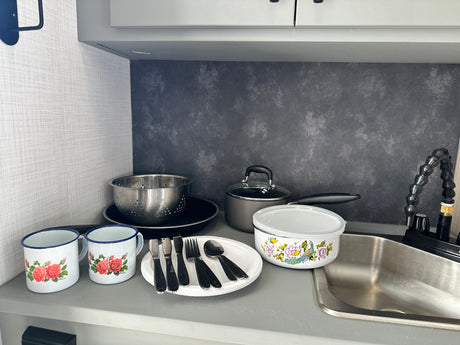 Compact kitchen in an RV rental, complete with sink, pots, and floral enamel mugs for your adventures.