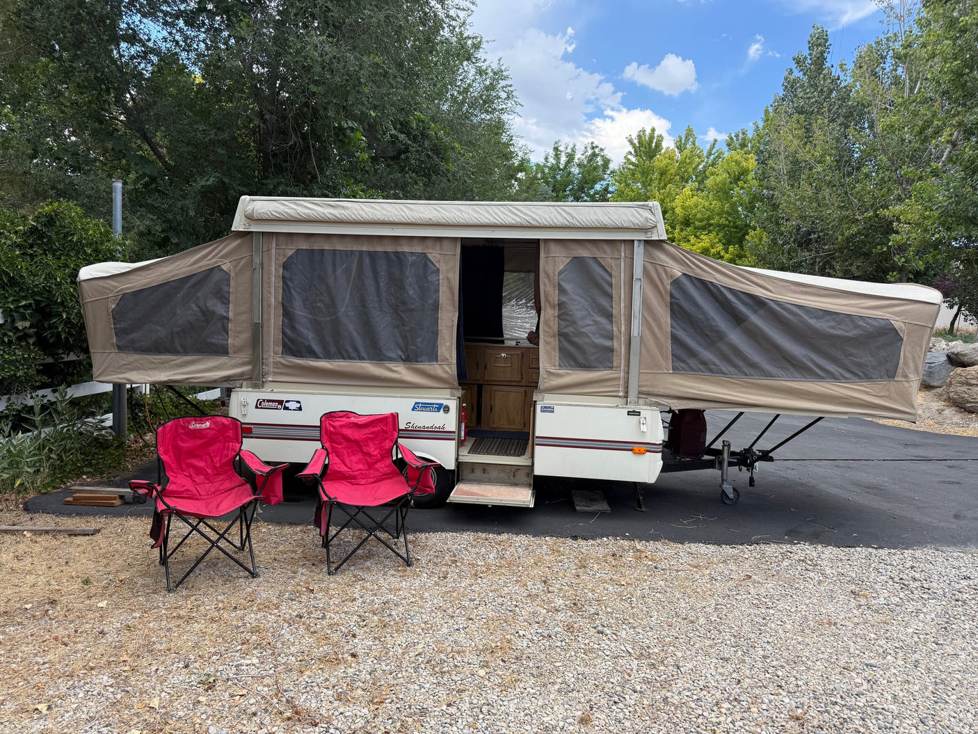 A fully set-up pop-up rv rental with two red chairs