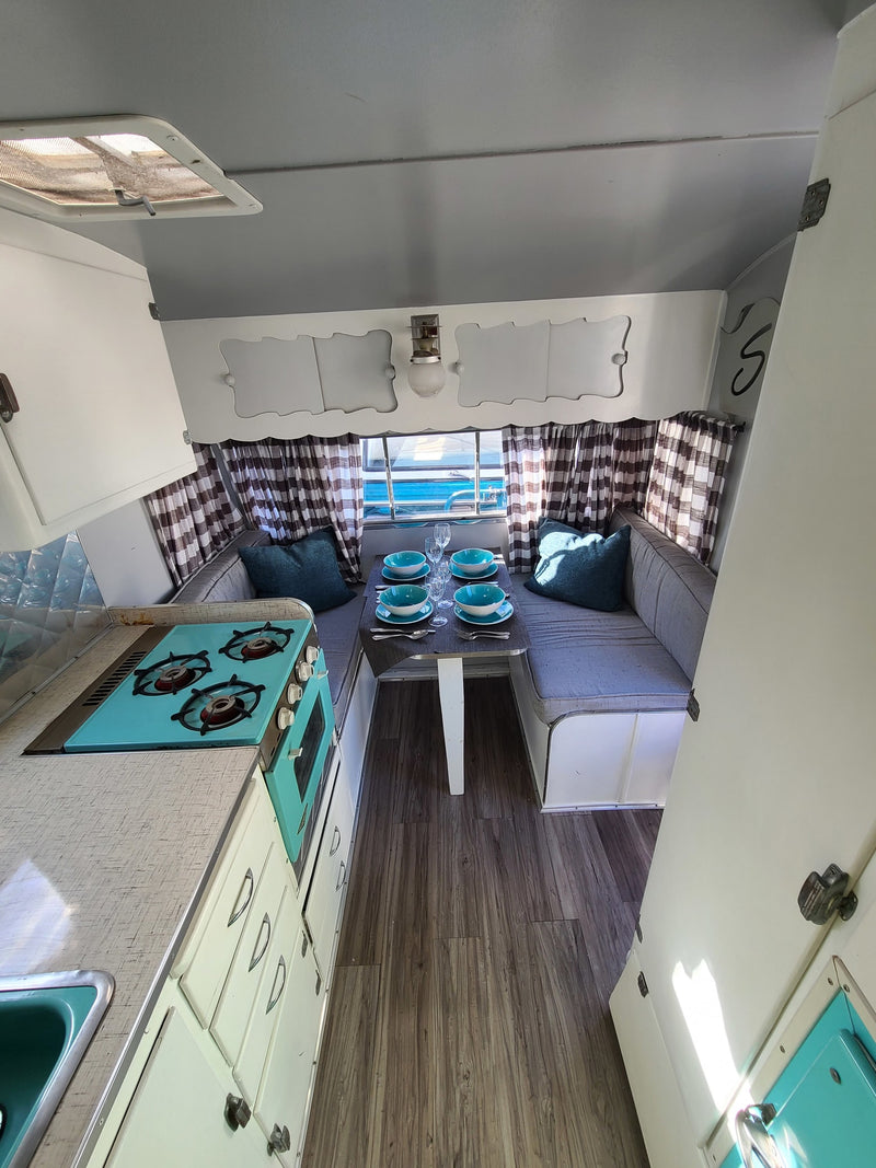 Experience a charming rv rental! This retro camper features a teal kitchen, set dinette, & checkered curtains for cozy trips. — photo 7