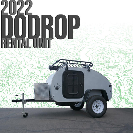 A grey 2022 DoDrop teardrop camper, an RV rental unit, shown with a roof rack and storage box, ready for adventure.