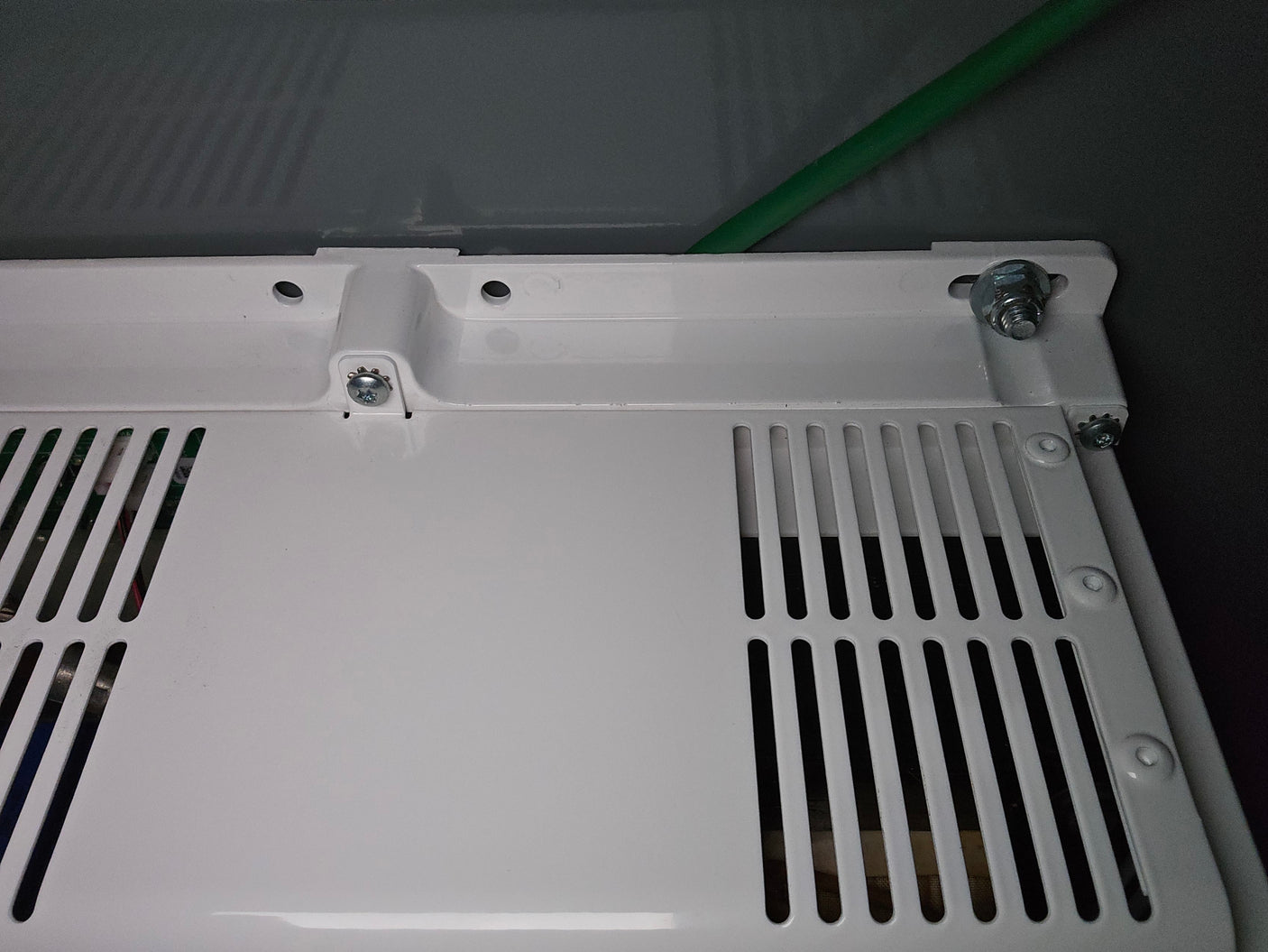 RV rental: Close-up of a white perforated vent panel, revealing interior wiring and a green cable connection.